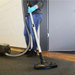 Cleaner vacuums the corridor of an office